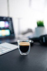 Espresso Coffee in minimalist desk office with keyboard, laptop, headphones and plant