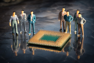 Group of miniature model of businessmen standing around the cpu in a reflective surface....