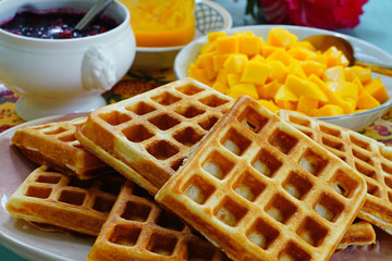 Plate of freshly baked waffles with fresh mango and berry compote for breakfast