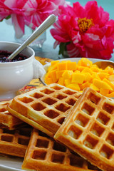 Plate of freshly baked waffles with fresh mango and berry compote for breakfast