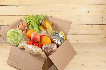 Food donations in the context of the coronovirus pandemic. Box with the necessary products, cereals, vegetables and fruits, stew and canned goods, delivery