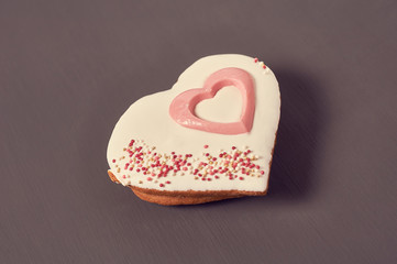 Gingerbread cookie in shape of heart with glaze on concrete surface. Concept of love or christmas....