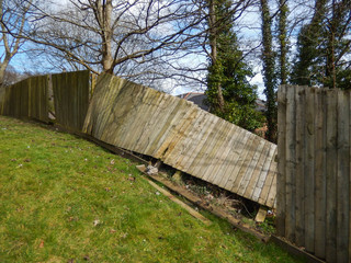 Wooden fence around a garden damaged by high winds