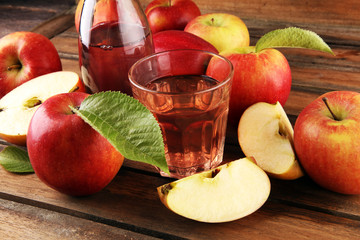 Apple cider drink and organic apples with leaves on table