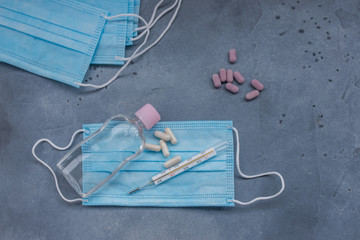 Medical mask, Medical protective mask, antiseptic, termometr, pills on blue background. Healthcare medical Disposable surgical face mask cover mouth and nose. Coronavirus quarantine, hygiene concept