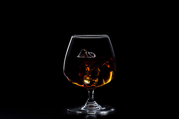 a glass of whisky with ice on black background