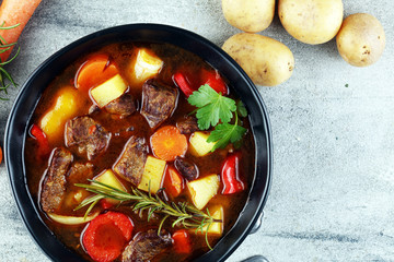 Meat stew with vegetables. Beef stew with potatoes, carrots and fresh herbs on table.