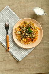 Plate of pasta with mushrooms in a creamy sauce with spinach on a linen tablecloth on a napkin and a fork.