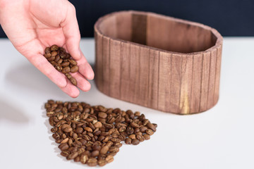 Coffee beans spilling out of a hand on a table, forming the shape of a heart