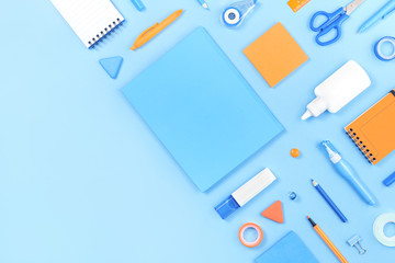Assorted office and school white orange and blue stationery on pastel background as corner border....