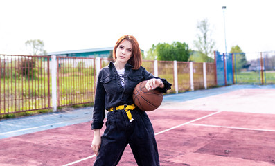 Young girl with red hair holds a basketball ball