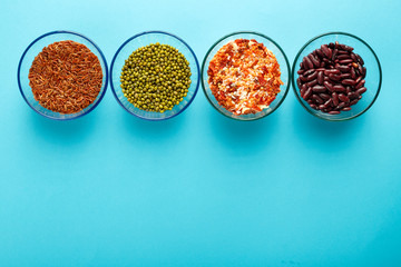 Obraz na płótnie Canvas Glass jars with cereal mung bean, lentils, beans, brown rice on a blue background.