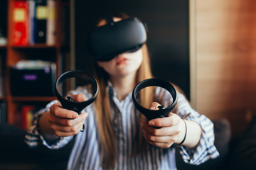 vr glasses. girl in VR glasses with two joysticks. girl in VR glasses on a dark background. girl holding VR glasses. girl on the background of the office