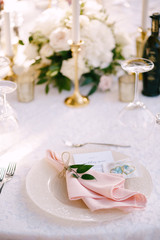 Wedding dinner table reception. Stone table with pink runner, plates with pattern and rag pink napkins, candles with led-light bulbs in the rays of sunset. Top view
