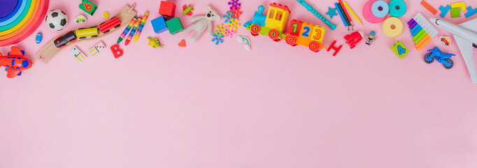 Frame of plastic and wooden kids toys on pink background