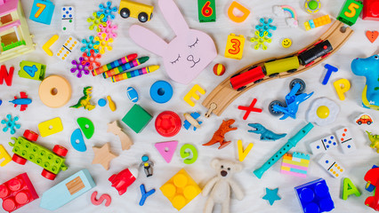 Variety of plastic and wooden kids toys on light wooden background