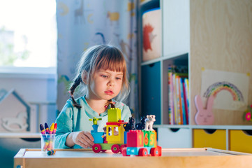 Little girl playing with kids plastic toy train