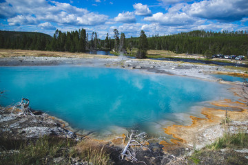 Basin with blue shade of thermal microorganisms inside with orange brown color by sides in Yellowstone National park United States, Travel background with geysers and hot springs, famous landmarks.