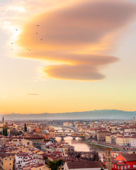 the famous bridge in Florence Ponte vecchio during the GOLDEN hour after sunset, the lights of the buildings reflect on river arno .Panoramic view from michelangelo square 