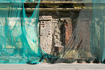 old brick wall covered with green mesh ( plastic cloth cover of building)