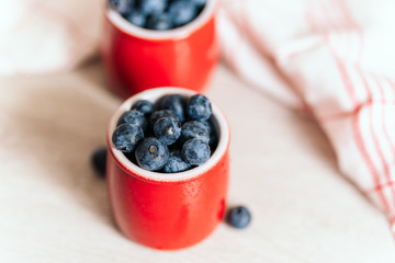 fresh blueberries in red pots on a wooden background, on a drop of water berries. healthy nutrition, vitamin charge, summer berries