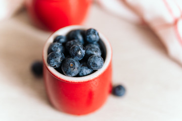 fresh blueberries in red pots on a wooden background, on a drop of water berries. healthy nutrition, vitamin charge, summer berries