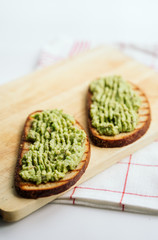 toasted bread with avocado paste. toast with avocado lies on a white plate and wooden cutting board. health food concept, vegan, vegetarian