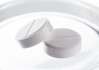two white round medical pills on white background