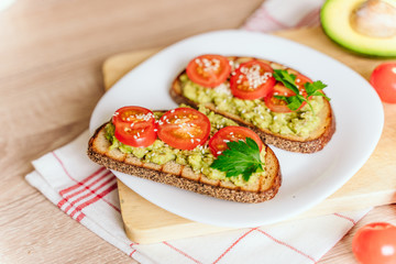 toasted bread with avocado paste and fresh tomato. Avocado mixed with lemon juice is spread on bread.  health food concept, vegan, vegetarian