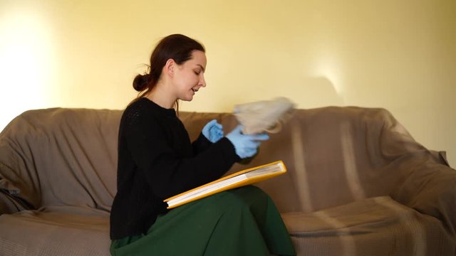 white woman takes off gas mask and leafs through a book laughing