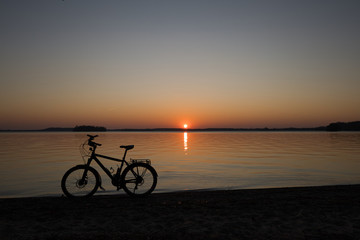Fototapeta na wymiar Fahrrad im Sonnenuntergang als Silhouette im Sonnenuntergang am Großen Plöner See Prinzeninsel