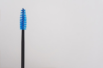 Blue and black eyelash brush. Copy space for text. Colorful eyelash brush in hand girl master eyelash extension. Professional makeup tools for eyelashes and eyebrows. Beauty concept in salon and shop