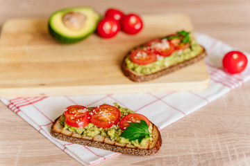 toasted bread with avocado paste and fresh tomato. Avocado mixed with lemon juice is spread on bread.  health food concept, vegan, vegetarian