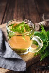 Healthy medicinal drink, nettle tea in a glass cup, decorated with fresh leaves