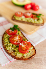 toasted bread with avocado paste and fresh tomato. Avocado mixed with lemon juice is spread on bread.  health food concept, vegan, vegetarian