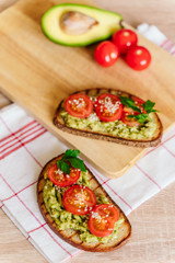 toasted bread with avocado paste and fresh tomato. Avocado mixed with lemon juice is spread on bread.  health food concept, vegan, vegetarian