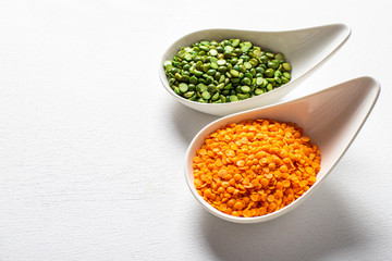 two types of legumes, beautifully arranged in cups and on a white background - green peas and orange lentils. Top view. copy space. Vegetarian food.