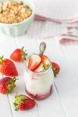 White fruity yogurt in jar and strawberries.
