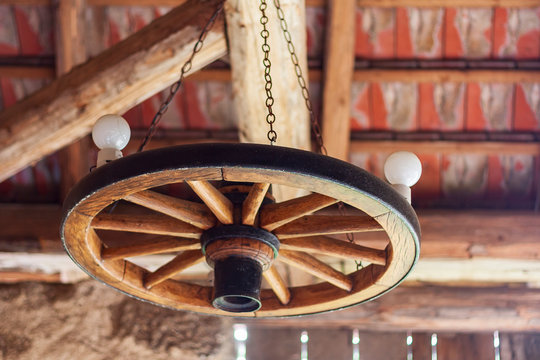 A wooden wheel suspended at the ceiling of a barn that functions as a light