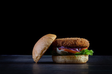 Chicken burger with lettuce, tomato, purpple onion and handmade mayo on the wood table. Delicious.