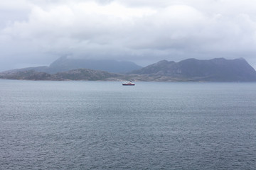 ship to visit fjords in Norway. A mystical fjord with dark clouds in Norway with mountains and fog hanging over the water