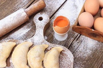 Baking cake in rural kitchen - dough recipe ingredients eggs, flour, milk, butter, sugar on vintage wooden table from above. Background layout with free text space.