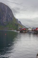 Red fishing rorbu huts and fishing boat in town of Reine on Lofoten islands