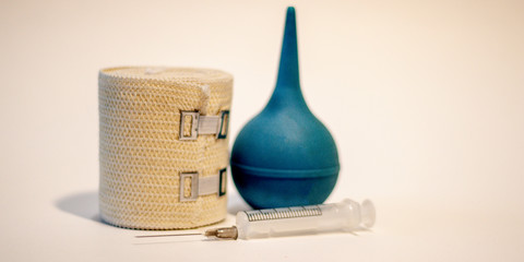 Medical equipment on a white background. Enema, syringe, bandage. Medical concept, side view.