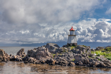 Fototapeta na wymiar Lighthouse in Norwegian fjords, Norway. Sea mountain landscape view.