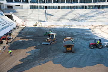 Stadium construction. Construction equipment and workers on the construction of a football stadium
