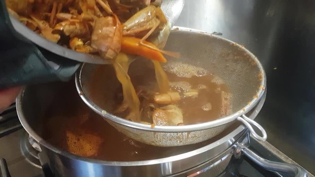 Preparation of bisque sauce. Tomato paste is added to the broth with prawns and mixed