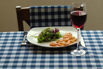 green salad with shrimp and wine on a table with a tablecloth