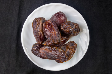 Big luxury dried date fruit in bowls on the dark surface, kurma ramadan kareem concept, close up.