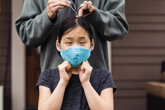 Woman tying strings of mask for girl